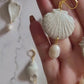 Closeup of shell shaped polymer clay Earrings on a white background. Earrings are made of pearlescent clay.