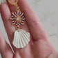 Close up of earrings with gold helm charm and polymer clay sea shell