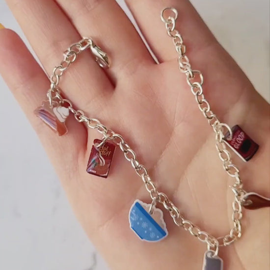 video close up of silver charm bracelet with thanksgiving themed charms on a marble background. 