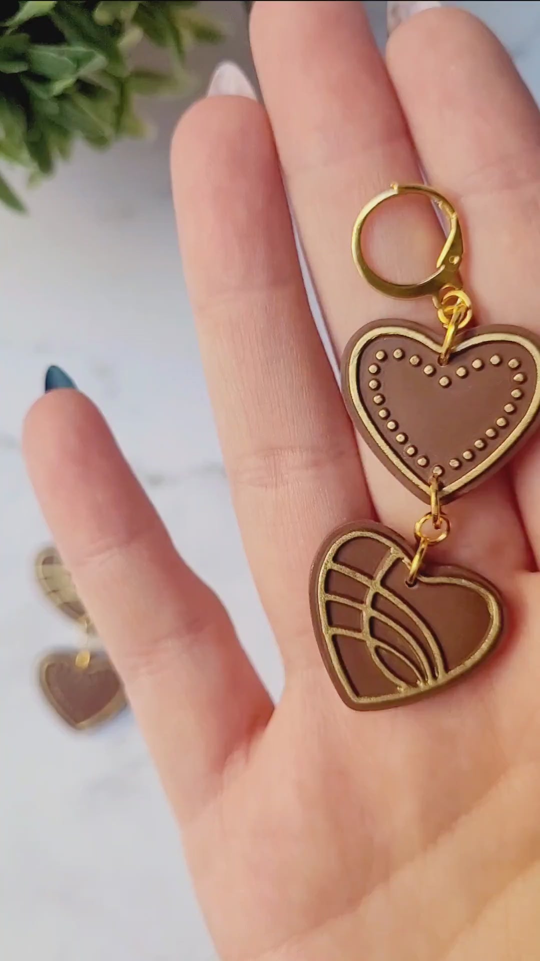 video close up of Chocolate and gold heart truffle earrings on a white background.