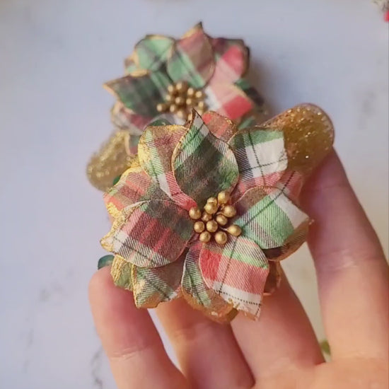 video close up of Christmas themed plaid poinsettia hair clip on a marble background. 