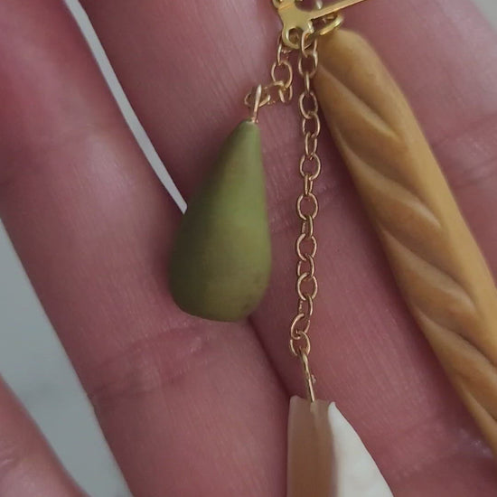 closeup of 3d Baguette, wedge of cheese, and pear earrings.