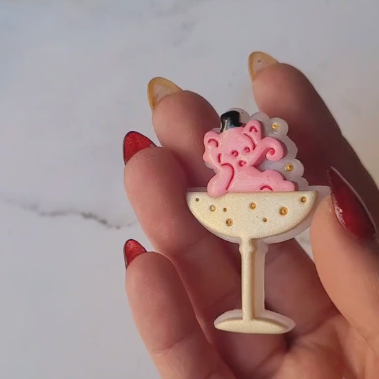 video close up of Pink Elephant in a champagne coupe brooch on a marble background .