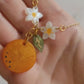 Closeup of resin orange blossom necklace in palm of hand to show size and color detail. 