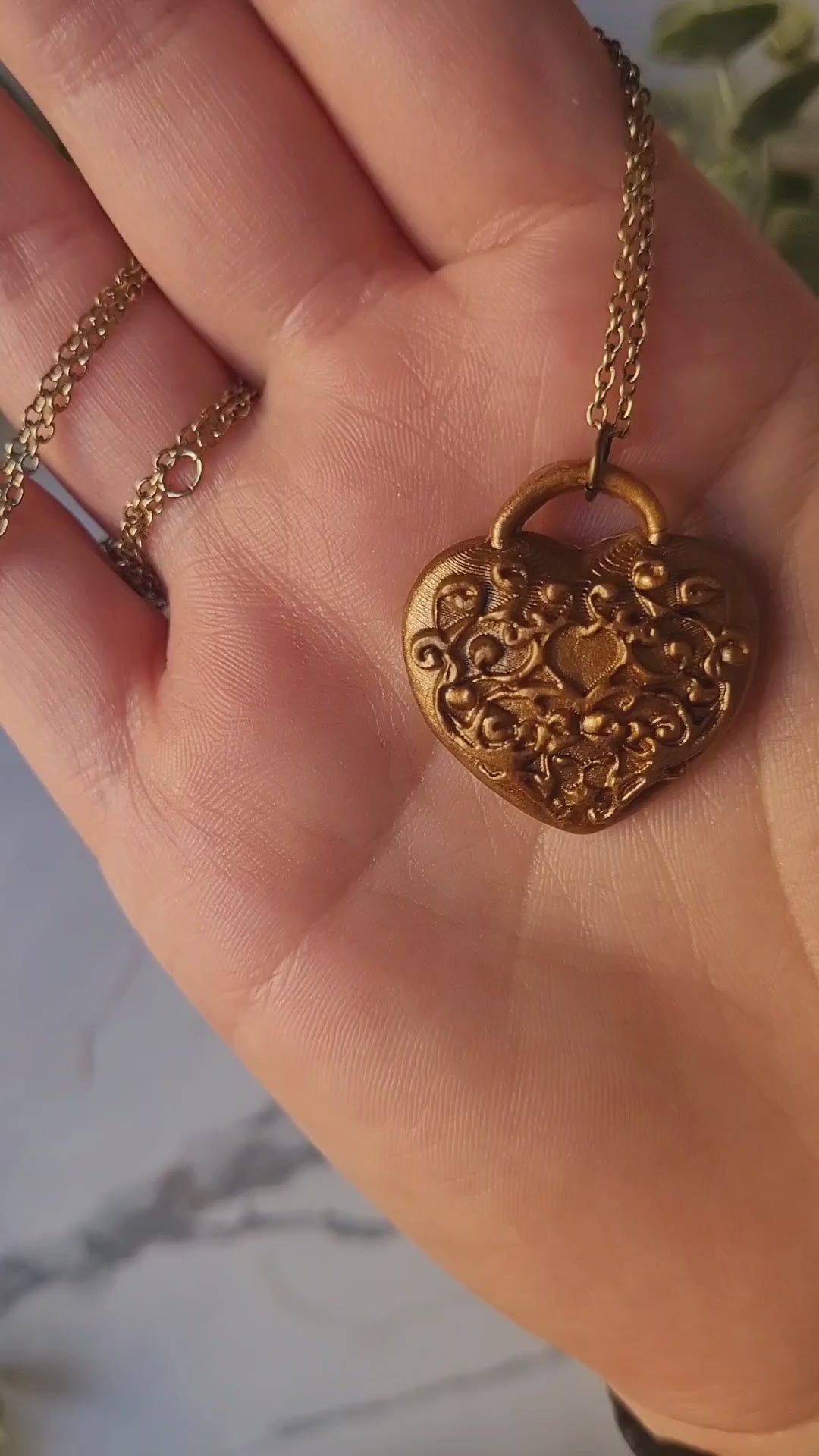 video close up of heart shaped lock pendant with filigree in antique gold 