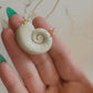 Close up in hand of polymer clay necklace on a white background. Necklace is made of pearlescent clay.