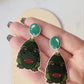 video close up of creature of the black lagoon earrings on a marble background.