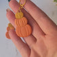 video close up of Triple stack pumpkin earrings on a marble background with fall foliage.