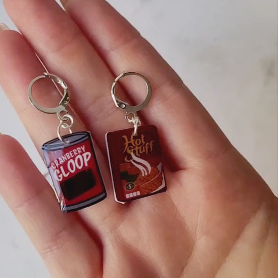 video close up of Cranberry sauce and stuffing box earrings on a marble background with fall foliage.