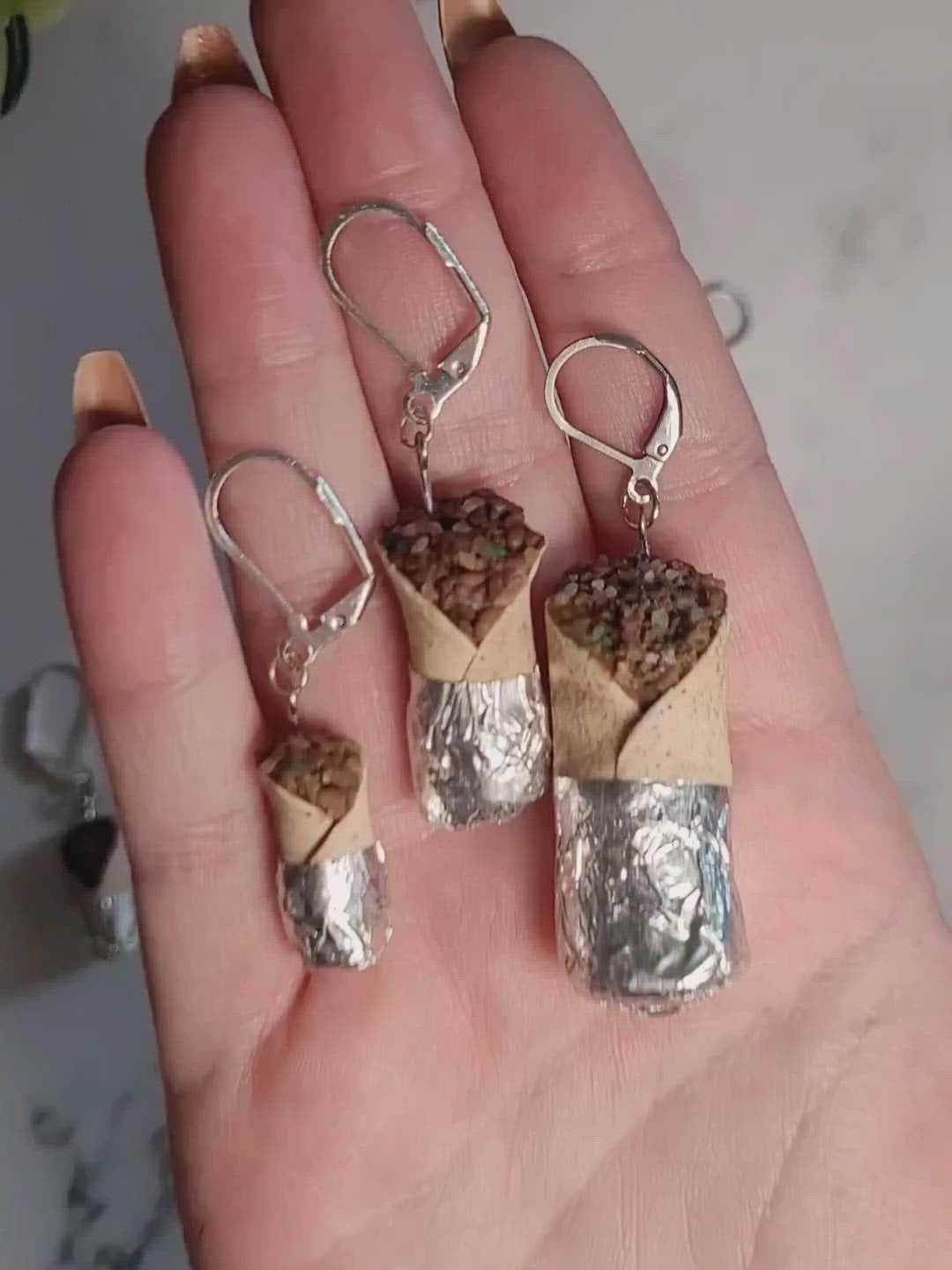 Closeup of the three burrito earring sizes to show details while sitting in palm of hand. 