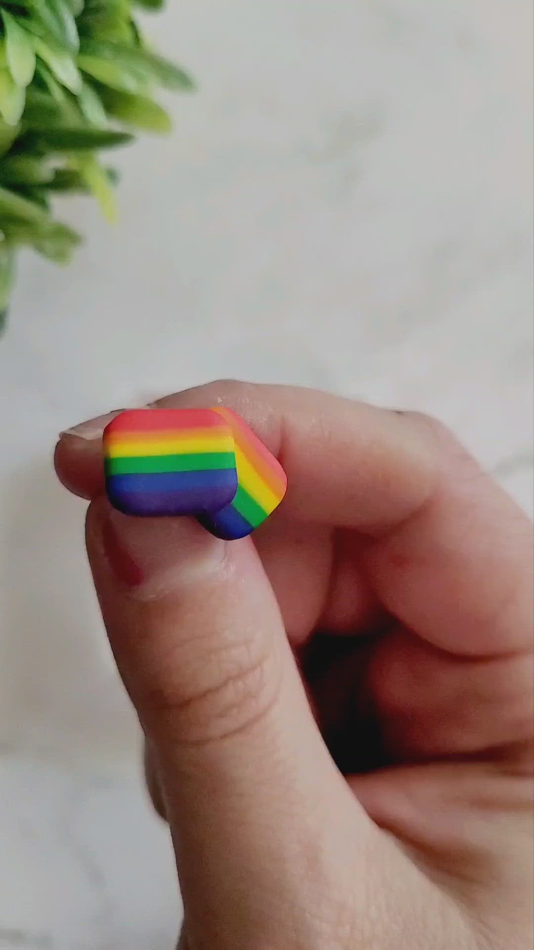 closeup of Rainbow stripe clay in shape of pride flag stud.