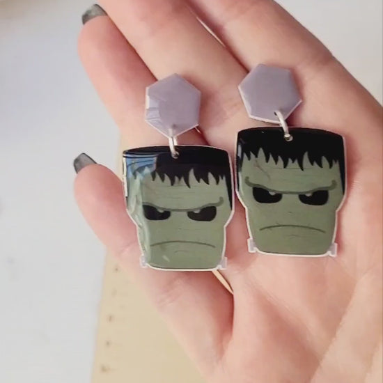 video close up of Frankenstein dangle earrings on a marble background