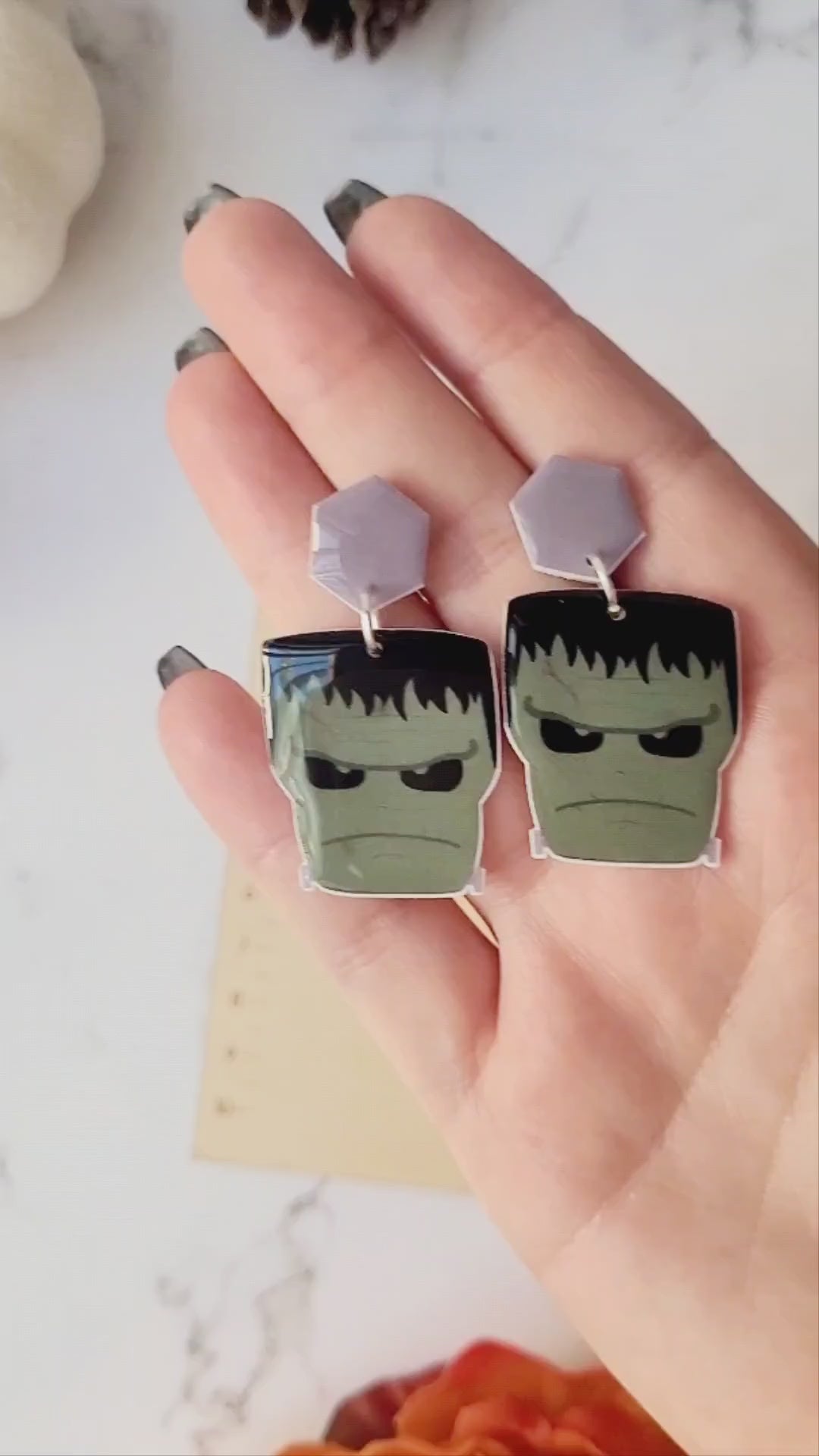 video close up of Frankenstein dangle earrings on a marble background